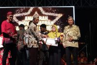 Kepala Bidang Pelayanan Pendaftaran Penduduk Disdukcapil Sumenep, Wahasah, saat menerima penghargaan inovasi daerah yang diberikan oleh Plt Sekda R. Achmad Syahwan Effendy (Za - garudajatim.com)