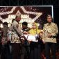 Kepala Bidang Pelayanan Pendaftaran Penduduk Disdukcapil Sumenep, Wahasah, saat menerima penghargaan inovasi daerah yang diberikan oleh Plt Sekda R. Achmad Syahwan Effendy (Za - garudajatim.com) 