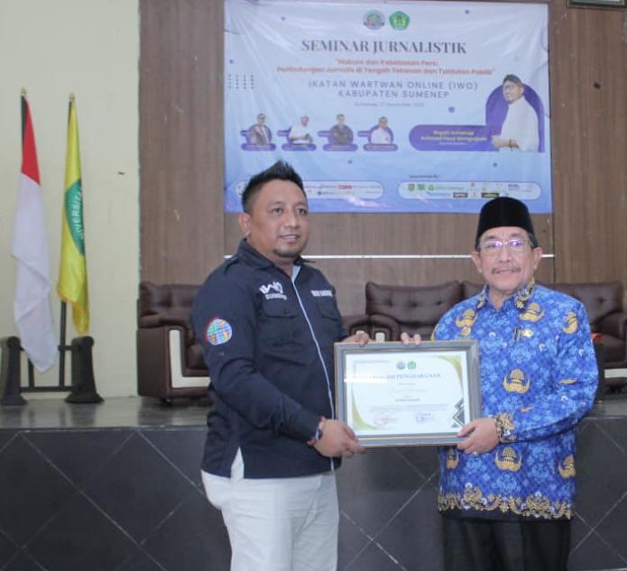 Ketua IWO Sumenep, Imam Mustain Ramli, saat menyerahkan penghargaan kepada Wakil Bupati Imam Hasyim (Za - garudajatim.com)